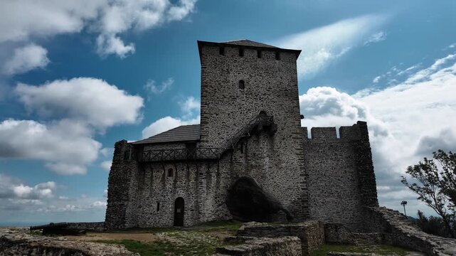 Vrsac Fortress stone tower and walls under blue sky with clouds in Serbia. Medieval stronghold landmark standing on the hill above the town
