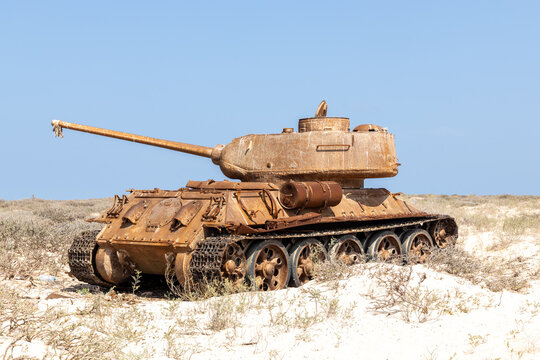 View of sun-bleached sand cradles a decaying tank, its rusted armor a stark contrast to the azure sky, whispering tales of forgotten conflicts, Qalansiyah, Socotra, Yemen.