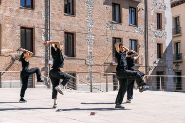 Obraz premium Dynamic street dance group performing a synchronized routine in an urban setting, expressing freedom and artistry