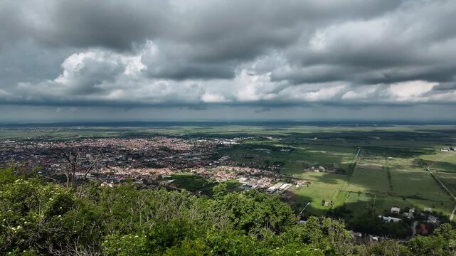 Panoramic view of Vrsac and surrounding plains from the hilltop in Serbia. Dramatic clouds cast shadows over farmland and town under a wide Balkan sky