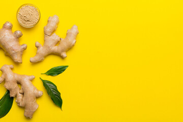 Fototapeta premium Finely dry Ginger powder in bowl with green leaves isolated on colored background. top view flat lay