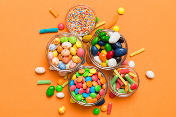 different colored round candy in bowl and jars. Top view of large variety sweets and candies with...