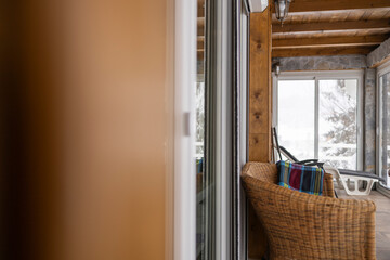 Cozy Mountain Lodge Interior with Wicker Chair and Snowy Terrace View