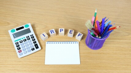 On the desk, an IRPEF sign in Italian on wooden cubes. Personal Income Tax. Top view of office...