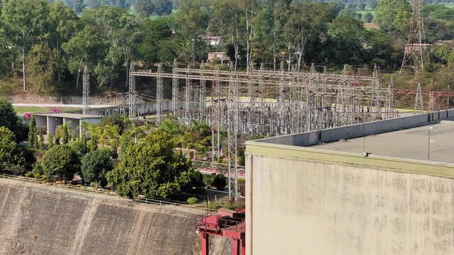 Static shot shows the power grid supporting electricity generation at Bargi Dam in Jabalpur, with transmission towers, substations, greenery, and concrete infrastructure.