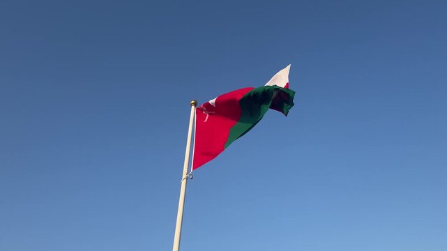 Waving oman flag against a clear sky