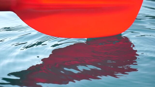 Paddle, water, ripples, red paddle dipping into tranquil blue water, creating serene waves, perfect for peaceful outdoor activity