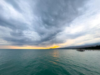 Obraz premium Sunset at Issyk Kul Lake in Kyrgyzstan. Bright sun breaking through clouds reflecting in clear turquoise water.