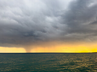 Obraz premium Sunset at Issyk Kul Lake in Kyrgyzstan. Bright sun breaking through clouds reflecting in clear turquoise water.