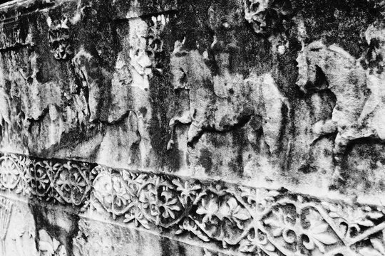 Close-up black and white photograph of a medieval stećak tombstone featuring a carved horseman relief. Weathered limestone texture with cracks and erosion details. Cultural heritage monument from the 