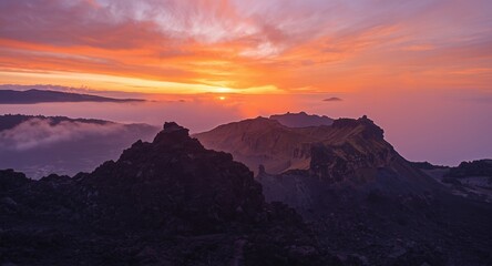 Obraz premium Glorious sunrise revealing volcanic shapes surrounded by colorful sky and mist