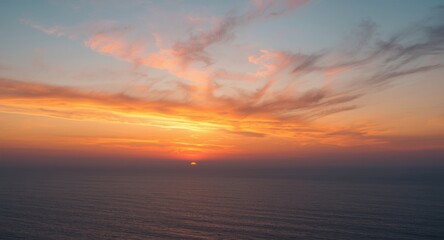 Obraz premium placid sea horizon under a sky painted with clouds and warm sunset hues