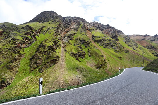 Winding Asphalt Road through Green Mountain Slopes at Stelvio Pass, Italy