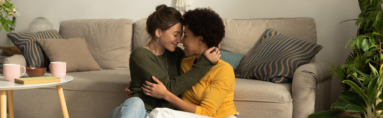 Fototapeta premium Two women share a tender moment of love and connection on a cozy couch at home
