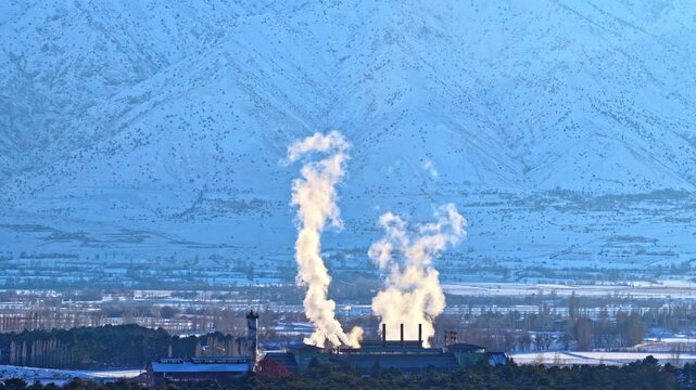 Smoke Rising from Sugar Factory in Snowy Mountain Landscape