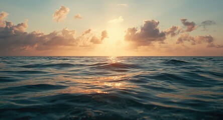 Obraz premium Relaxed ocean water illuminated by warm sunlight under a bright sky with soft cloud coverage at dusk