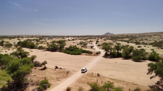 Drone Footage of White SUV Driving on African Riverbed and Sand Road with Mountain Landscape &ndash; Namibia 4K