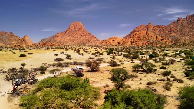 Drone Footage of White Cars Driving on African Sand Road Towards Lodge with Mountain Landscape &ndash; Namibia Adventure 4K