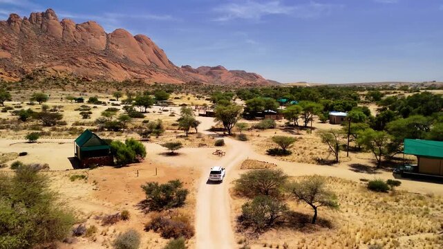Drone Footage of White Cars Driving on African Sand Road Towards Lodge with Mountain Landscape &ndash; Namibia Adventure 4K