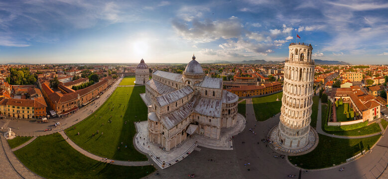 View of the Leaning Tower, Baptistery, and Cathedral basking under a bright sun, casting long shadows across the green lawns, Pisa, Toscana, Italy.