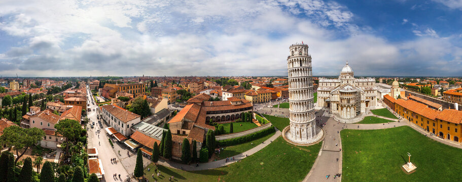 View of the Leaning Tower of Pisa and Duomo rise majestically from the lush green Piazza del Duomo, a timeless scene under a partly cloudy sky, Pisa, Toscana, Italy.