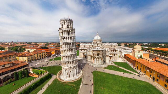 View of the iconic Leaning Tower of Pisa stands tall against the azure sky, surrounded by lush green lawns and historic buildings, Pisa, Toscana, Italy.