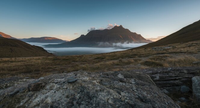 Balmy evening in highland valley showing stone foreground and mountain ridge silhouette closeup vertical