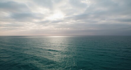 Fototapeta premium Vast ocean under a cloudy sky with soft sunlight