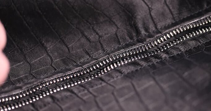 black artificial fabric in the style of crocodile skin with specks , a close-up of a piece of clothing made in the style of leather items made of artificial leather