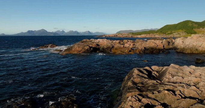Waves hitting the rugged and wild coast of Vesteralen archipelago in Norway. Aerial forward at low altitude