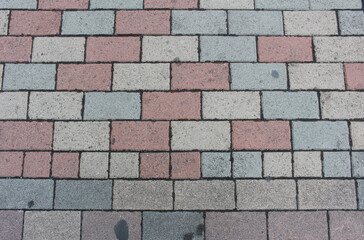 Obraz premium Texture of square paving tile. Pattern of red, brown, beige and grey sidewalk tiles in the street. Concrete pavers close up background.