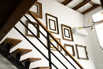 Staircase of a modern apartment with empty wooden frames on a wall.
