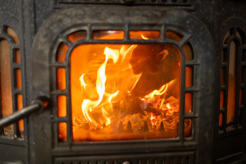 Detail of a cast iron furnace with a fire burning inside.
