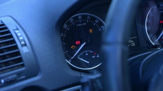 A car dashboard shows various warning lights glowing in the dim evening light. Car dashboard lighting before engine starts.