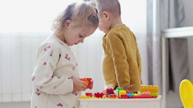 Two young children are engaged in playtime with colorful building blocks. They focus on stacking and arranging the blocks in a well-lit indoor area