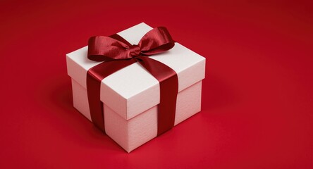 Fototapeta premium Elegant white gift box featuring a ruby ribbon displayed on a bright red background ideal for celebrations