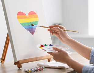 Artist painting a large LGBT pride rainbow heart on canvas