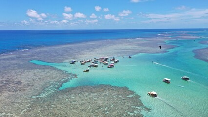 Obraz premium Fantastic aerial view of the turquoise waters of Toque beach with dozen of small boats with tourists on the natural pools formed among coral reefs in Milagres route near Maceio, Alagoas State, Brazil 