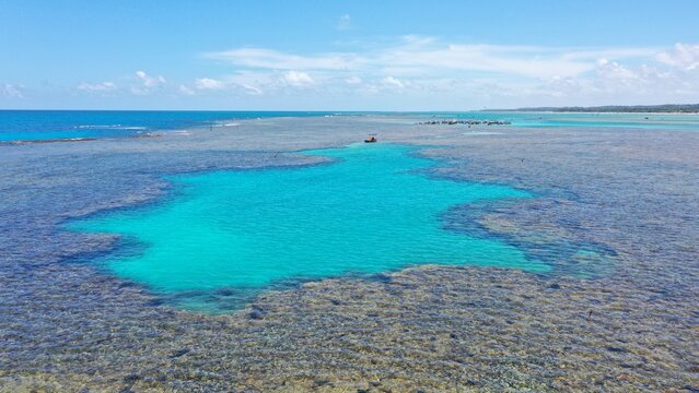 Fantastic aerial view of the turquoise waters of Toque beach with dozen of small boats with tourists on the natural pools formed among coral reefs in Milagres route near Maceio, Alagoas State, Brazil 