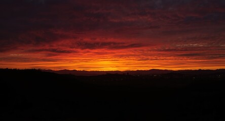 Sunset panorama showing darkened city outlines beneath vibrant clouds