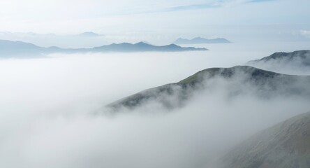 Obraz premium Soft white fog blanketing vast mountain landscape