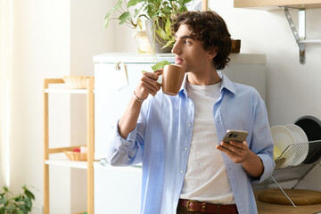 Handsome young man enjoying a cozy moment at home with a coffee and phone