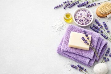 A soothing spa setup featuring lavender flowers, purple towels, natural soap, bath salts, and essential oil on a light background, perfect for relaxation and self-care.