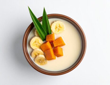 A bowl of kolak sweet takjil dessert with sliced bananas and jackfruit in a creamy milk, served in a wooden bowl from a top view