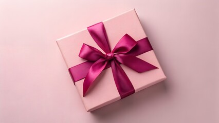 Fototapeta premium Top view of an elegant light pink square gift box with a textured surface, decorated with a large fuchsia satin ribbon bow, isolated on a matching pastel pink background with soft shadows.