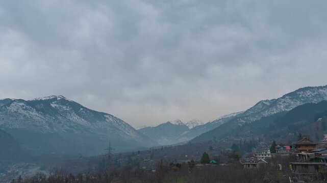 4K Time-lapse shot of dark clouds above the snowy Himalayan mountain range during a winter storm as seen from Naggar near Manali in Himachal Pradesh, India. Dark stormy clouds above Himalayas.