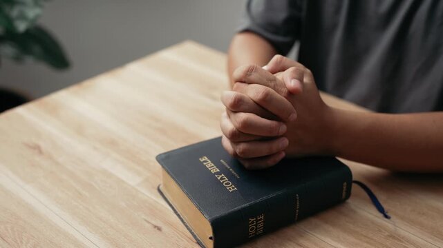 Hands clasped prayer with Holy Bible for Christian faith, spirituality, worship, devotion, hope, and religious belief, prayer time in church, trust in God, and spiritual guidance.