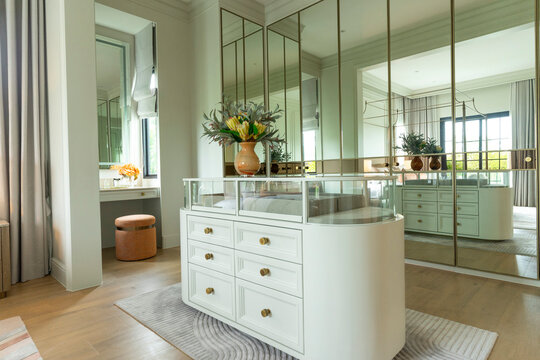 Luxury modern walk-in closet with mirror cabinets facades and island console.