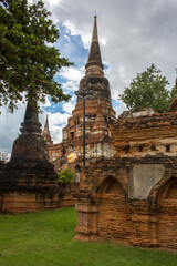 Fototapeta premium Low-angle shot of the grand central chedi at Wat Yai Chai Mongkhon in Ayutthaya, Thailand. The ancient bell-shaped structure, built from weathered red brick, towers into a dramatic sky.
