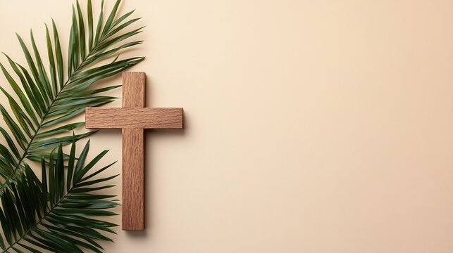 wooden cross and palm leaf on a beige background, with copy space for a concept related to christian holidays such as easter, christmas day, palm sunday, blank area for text.